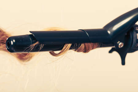 Stylist curling hair for young woman. Girl care about her hairstyleの写真素材