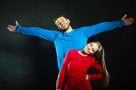 Portrait of smiling woman and man in sportwear posing in studio on black. Happy joyful couple. Good relationship.の写真素材