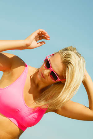 Young blonde pretty girl on beach. Woman wearing sunglasses have active time in summer. Summertime concept.の写真素材