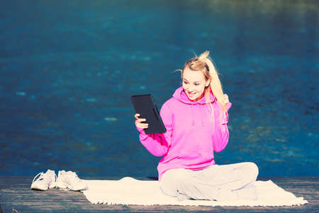 Young pretty girl at park work with computer. Woman sitting and mobile work on fresh air using tablet to video call. Health care in job.の写真素材