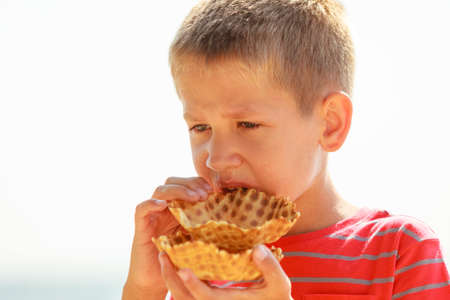 Sweets and candy food. Little boy kid with sweet meal outdoor. Male child enjoying eating his dessert outside in sunny weather.の写真素材