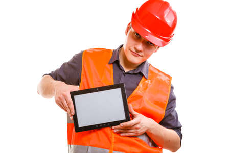 Technological development in company. Young handsome man worker in safety vest and hard hat with tablet. Repairman inspector at work isolated on white.の写真素材