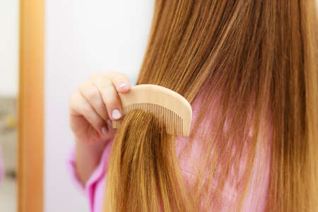 Woman combing brushing her long smooth hair close up. Girl taking care refreshing her hairstyle. Haircare concept.の写真素材
