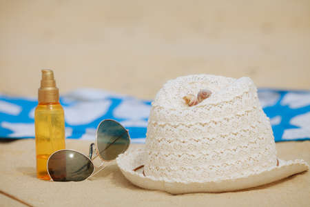 Beach set summer hat sunglasses and skin lotion lying on the sand. Vacation resting and relaxの写真素材