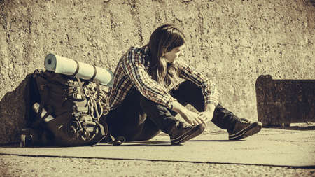 Man tourist backpacker relaxing outdoor sitting tired by grunge wall. Adventure, summer, tourism active lifestyle. Young hipster guy trampingの写真素材