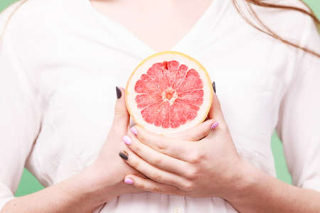 Woman holding half of grapefruit citrus fruit in hand. Healthy diet weight loss detox concept.の写真素材