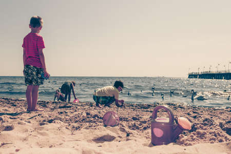 Joyful active childhood. Playful kids playing near water on seaside. Children having fun on summer beach. Young tourists spending actively time.の写真素材