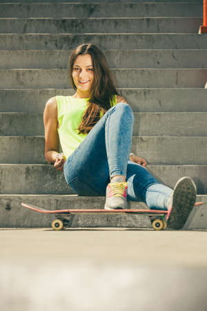Cool young long haired girl with skateboard sitting on the urban stairs. Active lifestyle funky in summer. Trendy sport teen.の写真素材