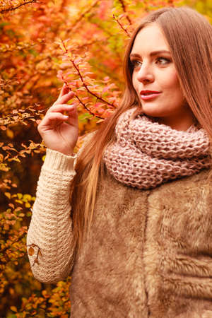 People, clohthing autumn season ceoncept. Attractive woman in the park. Long haired lady standing next to the bush outside.の写真素材