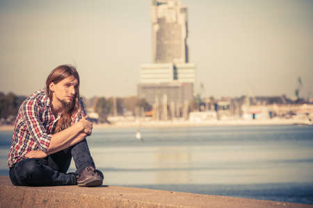 Man bearded long hair wearing plaid shirt casual style relaxing by seaside at summer sunny windy dayの写真素材