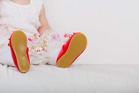 Lesson of walking. Part body baby girl little child toddler wearing princess dress with red small shoes.の写真素材