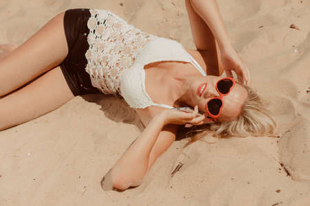 Young girl on beach with sunglasses talking using cellular phone. Communication and internet concept.の写真素材
