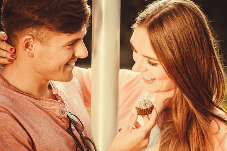 Love and dating. Young handsome man flirting with attractive woman by cupcake cookie. Happy cute lovers on date outdoor.の写真素材