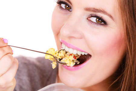 Woman eating oatmeal with nuts and dried fruits for breakfast. Girl holds plastic container take homemade lunch with healthy eating. Dieting nutrition conceptの写真素材