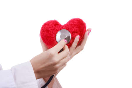 Medical examination of cardiology. Hands of cardiologist with heart and stethoscope. Female doctor makes measurement heartbeat. Isolated on white.の写真素材