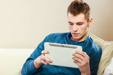 Modern technology leisure and relax concept. handsome man with pc computer tablet relaxing on couch