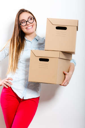 Happy woman moving in carrying cartons boxes. Young girl arranging interior and unpacking at new apartment house home.の写真素材