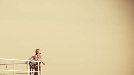 Man hiker backpacker on pier. Young guy tramping with backpack by seaside. Adventure and tourism. Beautiful sea landscapeの写真素材