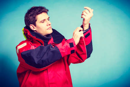 Young male getting dressed. Man putting on waterproof clothes. Adventure danger outdoors concept.の写真素材