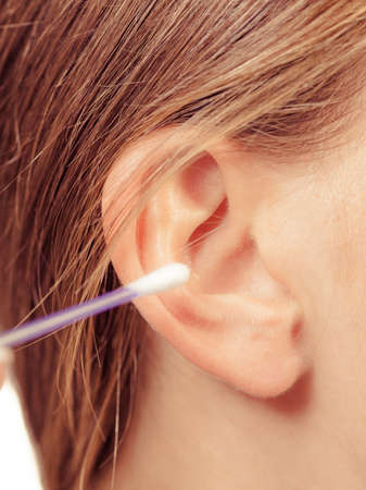 Hygiene concept. Woman cleaning ear with cotton swabs closeupの写真素材