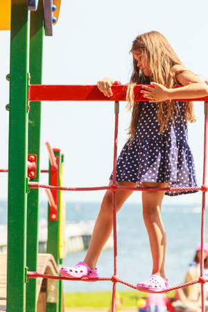 Time for fun. Summer holidays concept. Little funny girl having fun on playground. Child climbing. Enjoyable playful kid outdoors.の写真素材