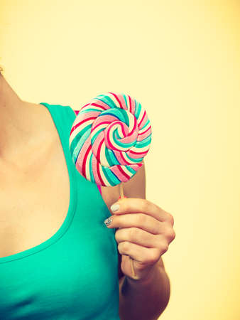 Woman holding colorful lollipop candy in hand. Sweet food and carefree concept. Studio shot on brightの写真素材