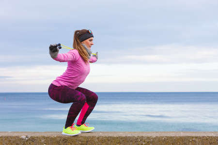 Woman athlete fit girl training outdoor with jumping skipping rope wearing warm sporty clothes in...