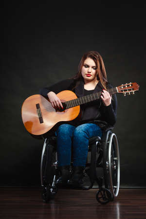 Song music handicap disability concept. Handicapped girl holding guitar. Crippled beautiful lady playing music enjoying her passion.の写真素材