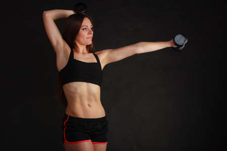 Bodybuilding. Strong fit woman exercising with dumbbells. Muscular long hair girl lifting weights on blackの写真素材