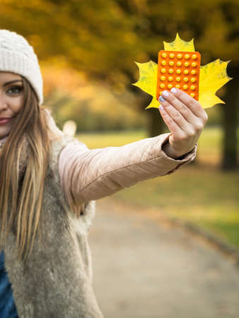 Healthcare concept. Beauty positive smiling woman with tablets pills and big gold leaf in autumnal...