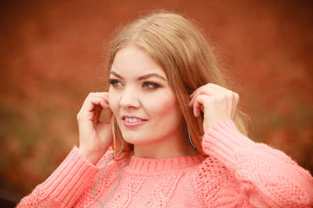 Autumn and people concept. Very beautiful girl in the park. Young woman with blonde hair wearing red sweather.の写真素材