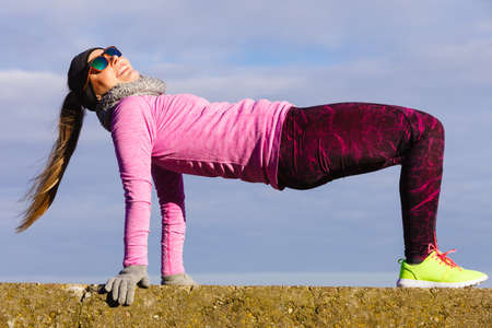 Woman athlete girl training wearing warm sporty clothes outside by seaside in cold weather. Sports...