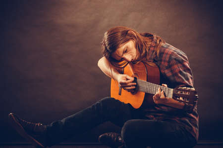 Music, hobby concept. Hippie with wooden guitar. Young man is playing the instrument.