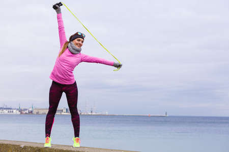 Woman athlete fit girl training outdoor with jumping skipping rope wearing warm sporty clothes in...