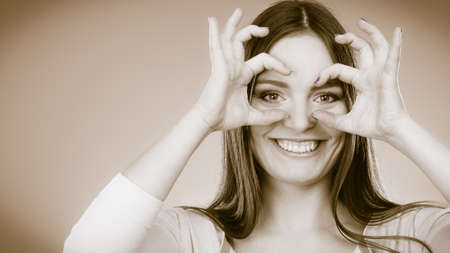 Closeup cute woman looking through imaginary binocular funny looking through fingers simulating...
