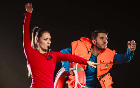 Lifeguards with rescue ring buoy lifebuoy and life vest jacket running to accident. Man and woman...