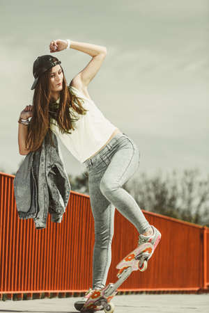 Summer sport and active lifestyle. Cool teenage girl skater riding skateboard on the street....