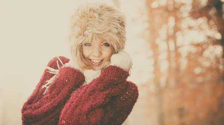 Portrait of pretty smiling fashionable woman in fall forest park. Happy gorgeous young girl in fur winter hat and sweater pullover.の写真素材