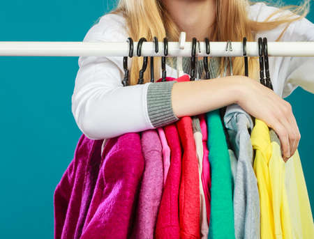 Woman grabbing clothing in wardrobe. Young undecided shopper girl takes all from mall shop....