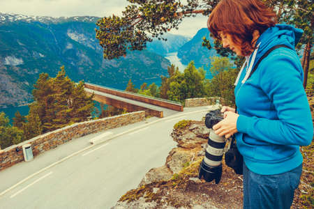 Tourism vacation and travel. Woman tourist taking photo with camera, enjoying Aurland fjord view from Stegastein viewpoint, Norway Scandinavia.の写真素材