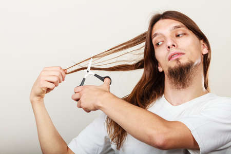 Trim and cut concept. Young handsome man cutting his hair. Change of look.  Barber and hairdresser.の写真素材