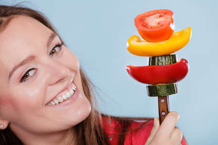 Fitness woman girl holding fork with fresh vegetables like tomato, pepper and cucumber. Dieting and slimming. Healthy nutrition.の写真素材
