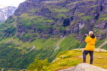 Tourism vacation and travel. Male tourist taking photo with camera, enjoying mountains landscape, Norway Scandinavia.の写真素材