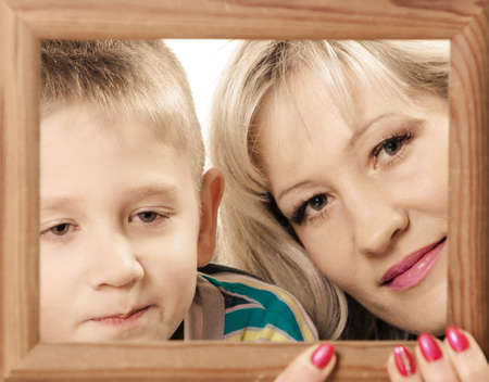 Spending time family bonds parenthood. Mother and son have fun play with empty picture frame hold in...