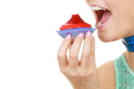 Woman smiling girl with blue measuring tape holds in hand cake cupcake. Weight loss dieting or sweet food and happiness concept.の写真素材