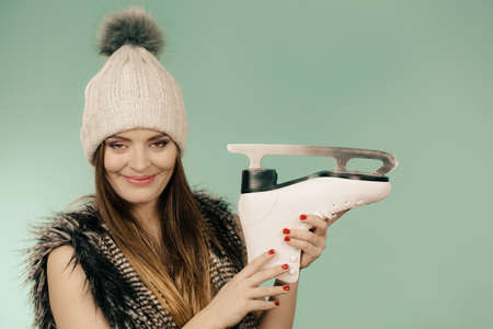 Winter, sport, people concept. Attractive lady with ice skates. Young woman wearing woolen cap.