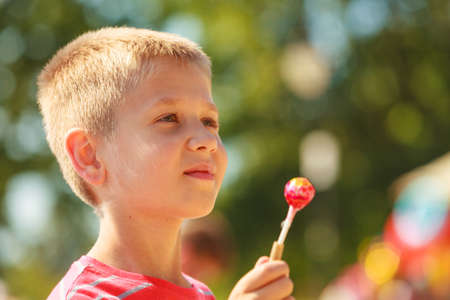 Sweets and candy food. Little boy kid with sweet meal outdoor. Male child enjoying eating his dessert outside in sunny weather.の写真素材