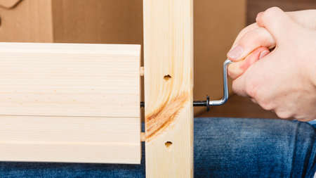 Human hand assembling wood furniture using hex key. DIY enthusiast. Home improvement.の写真素材