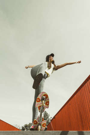 Summer sport and active lifestyle. Cool teenage girl in full length skater riding skateboard on the street. Outdoor.の写真素材