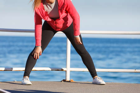Woman doing sports outdoors. Fitness girl in sportswear on seaside exercising keep her body muscles fitの写真素材